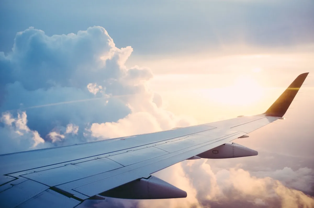Plane wing above clouds at sunset