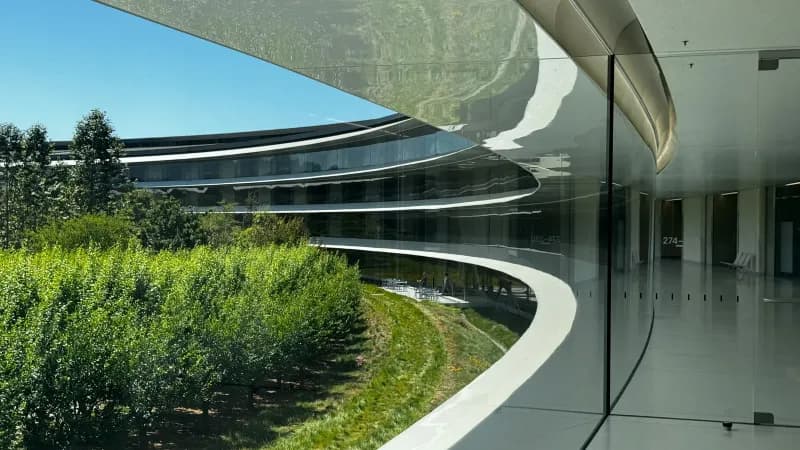 A curved building with trees and bushes in front of it